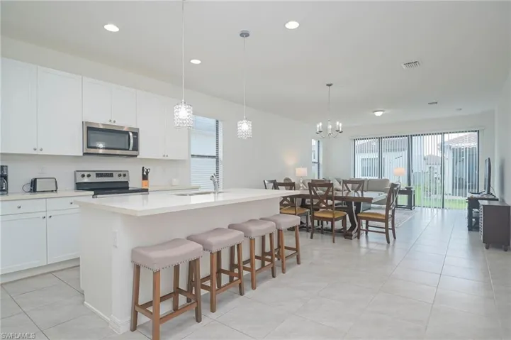 Kitchen featuring appliances with stainless steel finishes, a sink, healthy amount of natural light, a center island with sink, and recessed lighting