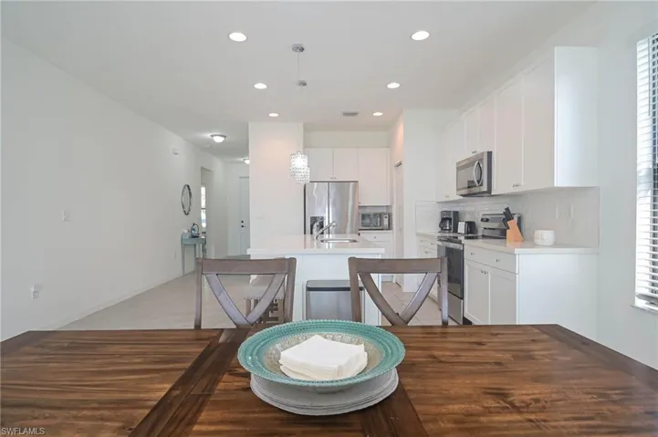 Kitchen with appliances with stainless steel finishes, a kitchen island with sink, decorative backsplash, white cabinetry, and recessed lighting