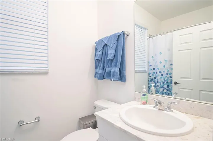 Full bathroom with vanity, toilet, and curtained shower