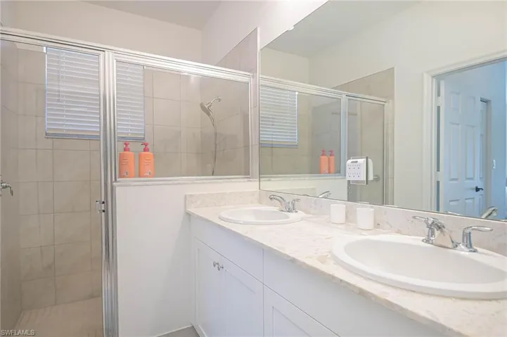 Full bath with a shower stall and double vanity