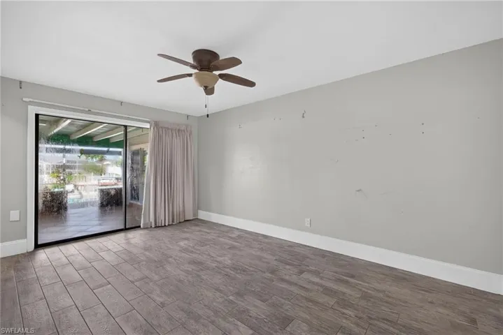 Wood-finish flooring, sliding glass door, overhead ceiling fan, and light gray wall paint