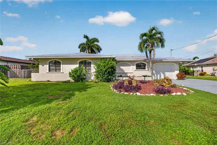 Single-story residence featuring a stucco exterior, arched windows, and an attached garage
