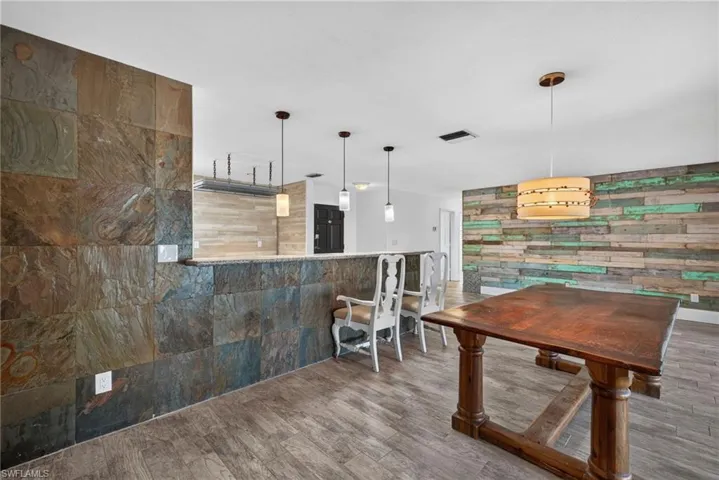 Stone-paneled accent wall, wood-look flooring, multiple pendant lights, and a textured accent wall