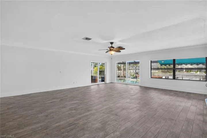 Expansive room with wood-finish flooring, white walls, and crown molding