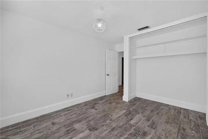 Wood-finish flooring, built-in shelving, white trim, and a decorative ceiling light fixture