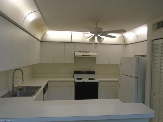 Kitchen with white cabinetry, ceiling fan, white appliances, and sink