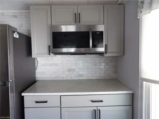 Kitchen with stainless steel appliances, gray cabinetry, and tasteful backsplash