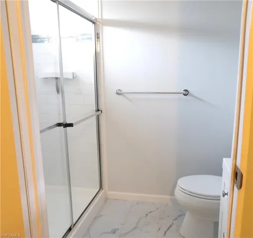 Bathroom featuring a shower stall, vanity, and light marble finish flooring