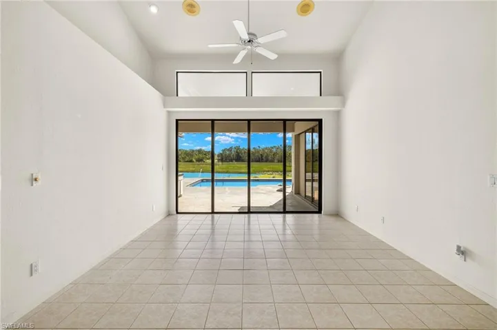 The living room features high vaulted ceilings and an entire wall of sliding glass doors and windows.