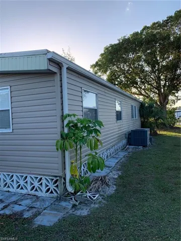 Property exterior at dusk with central air condition unit and a yard