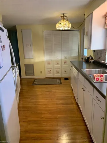 Kitchen with refrigerator, dark countertops, visible vents, dishwasher, and a sink