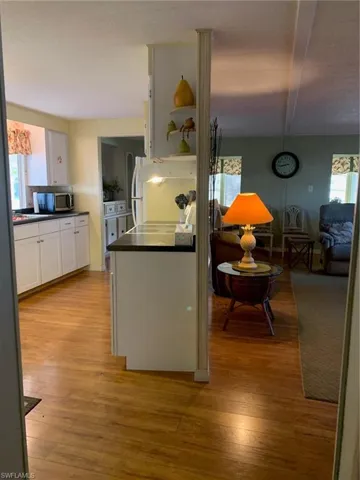 Kitchen featuring light wood-type flooring, dark countertops, open shelves, and white cabinets