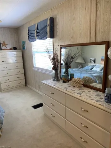 Bedroom with wood walls, light colored carpet, and visible vents