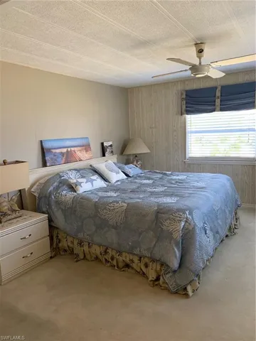 Bedroom with wood walls, carpet, a textured ceiling, and a ceiling fan