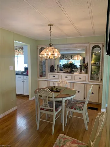 Dining space with a textured ceiling, wood finished floors, an inviting chandelier, and baseboards