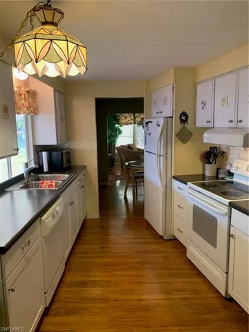 Kitchen featuring stove, dishwasher, dark countertops, extractor fan, and fridge