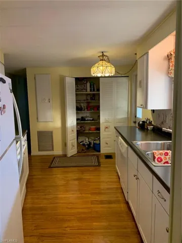 Kitchen featuring dark countertops, visible vents, dishwashing machine, fridge, and a sink