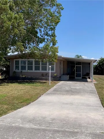 View of front facade featuring a front yard, a carport, and driveway