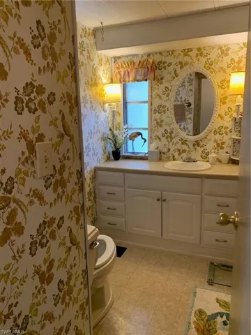 Bathroom featuring tile patterned floors, vanity, wallpapered walls, and toilet