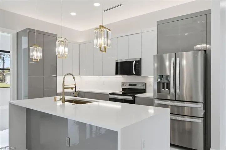 Kitchen with stainless steel appliances, modern cabinets, white cabinetry, pendant lighting, and light stone counters