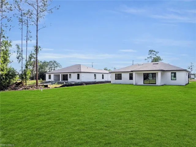 Rear view of property with a yard and stucco siding
