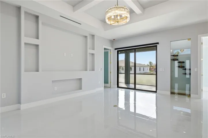 Empty room with coffered ceiling, beamed ceiling, and a chandelier