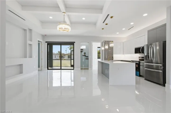 Kitchen featuring coffered ceiling, decorative light fixtures, appliances with stainless steel finishes, modern cabinets, and beamed ceiling