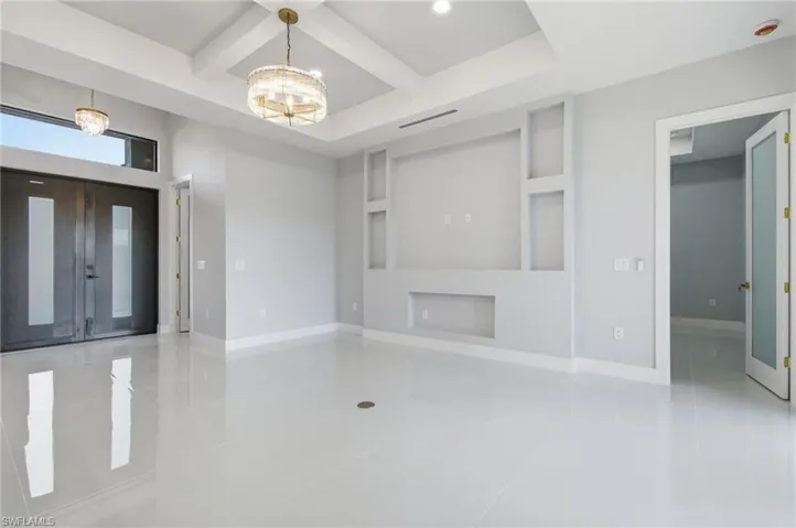 Unfurnished living room with coffered ceiling, built in shelves, light tile patterned floors, recessed lighting, and beam ceiling