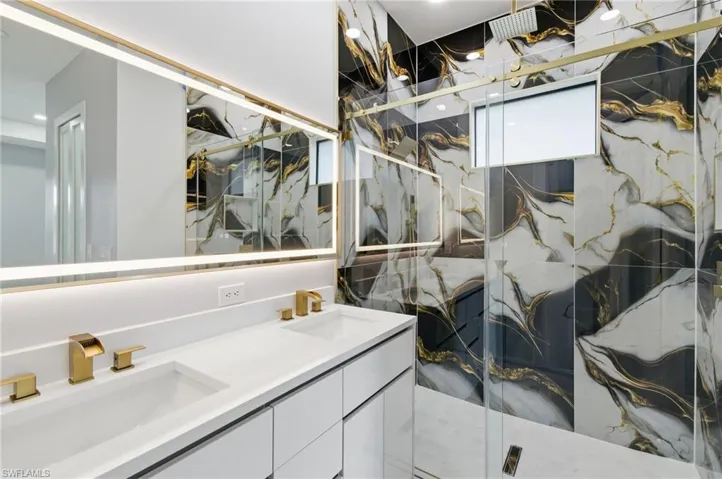 Bathroom featuring a marble finish shower and double vanity