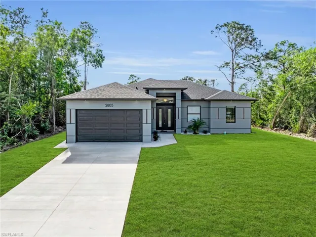 Prairie-style home with a front yard, stucco siding, and driveway