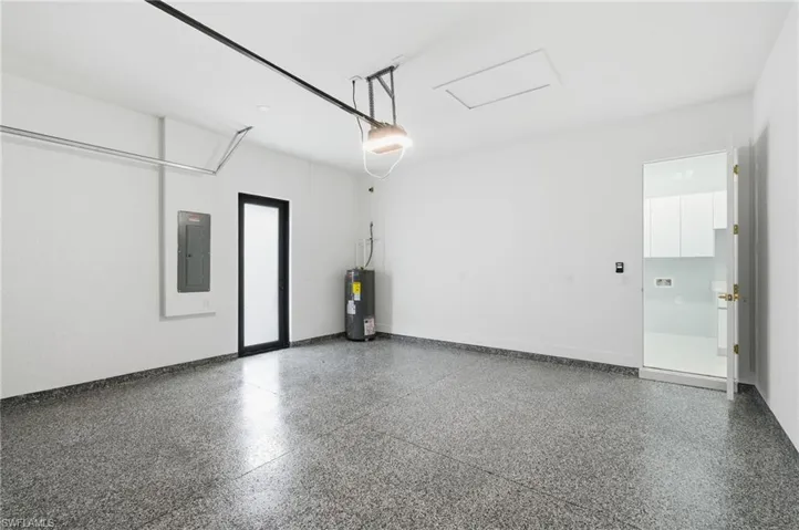 Garage featuring electric panel, electric water heater, and a garage door opener