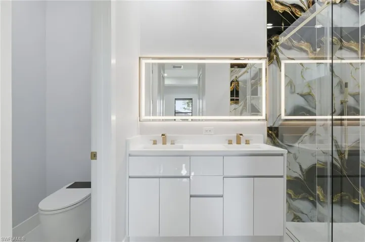 Bathroom with double vanity and a marble finish shower