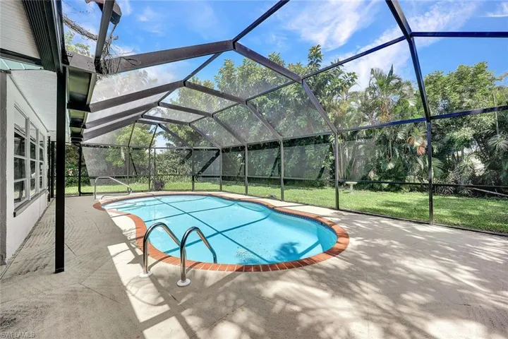 View of swimming pool featuring a patio, a yard, and glass enclosure