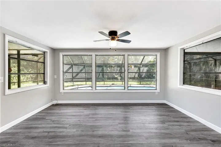 Spare room featuring ceiling fan, dark wood-type flooring, and plenty of natural light