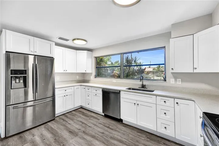 Kitchen with appliances with stainless steel finishes, light hardwood / wood-style flooring, sink, and white cabinetry
