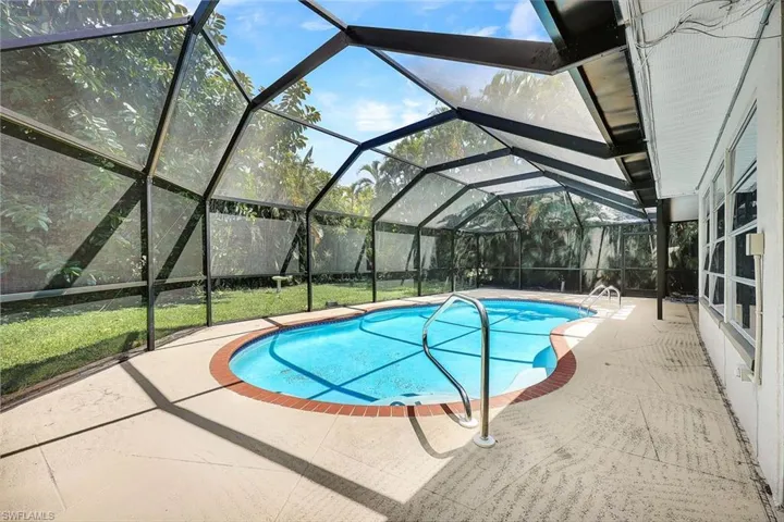 View of swimming pool featuring a patio, a lanai, and a lawn