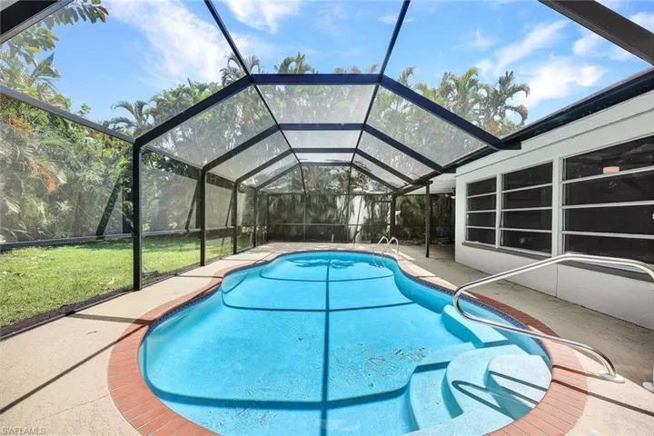 View of pool featuring glass enclosure, a patio area, and a yard