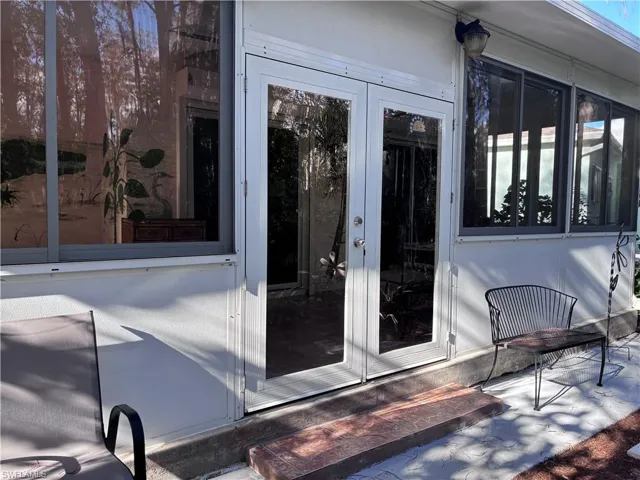 Property entrance with french doors, stucco siding, and a sunroom