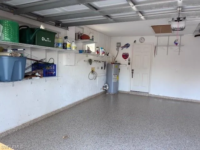 Garage featuring electric water heater and a garage door opener