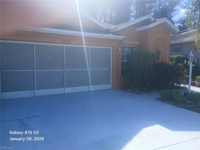 View of front facade featuring concrete driveway, stucco siding, a garage, and a patio