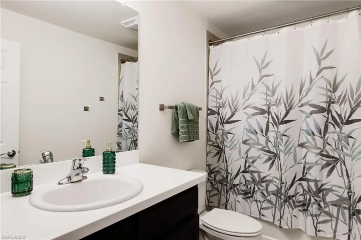 Bathroom featuring walk in shower, vanity, and toilet