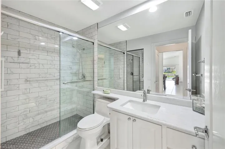 Full bathroom with visible vents, a shower stall, toilet, and vanity
