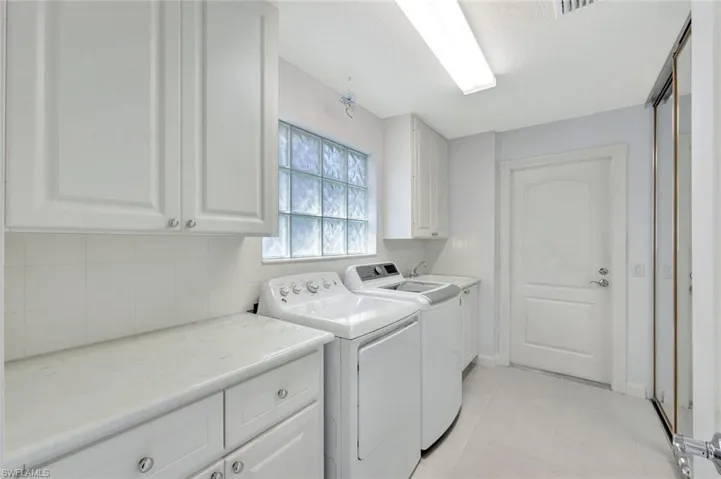 Washroom featuring light tile patterned floors, cabinet space, visible vents, independent washer and dryer, and baseboards
