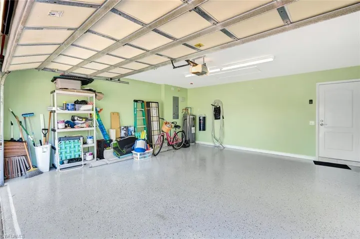 Garage with a garage door opener, electric panel, and baseboards