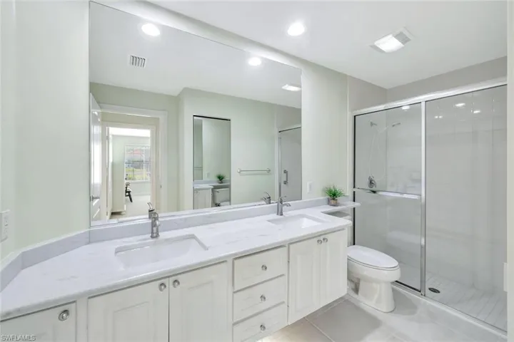 Full bathroom with toilet, tile patterned flooring, visible vents, and a sink