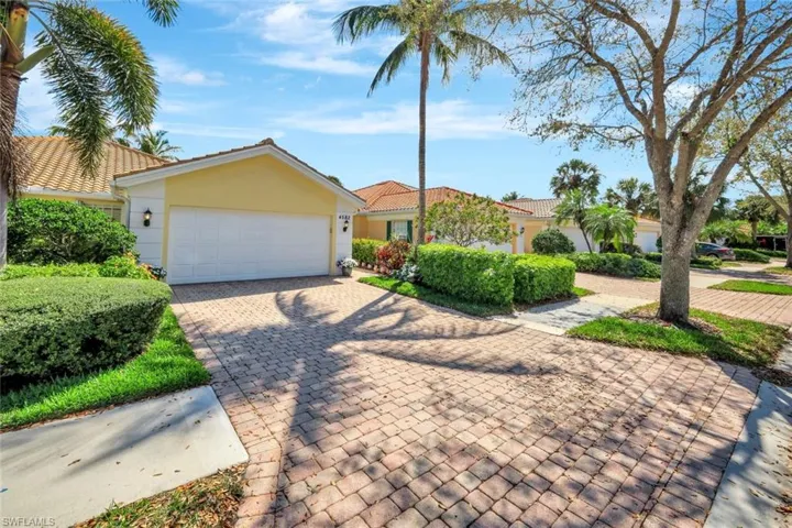 View of front of property featuring a garage, a tiled roof, decorative driveway, and stucco siding