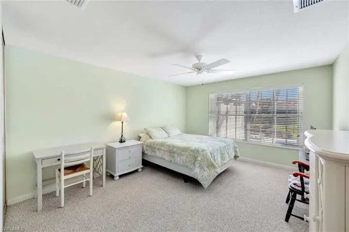 Bedroom featuring a ceiling fan, light colored carpet, visible vents, and baseboards
