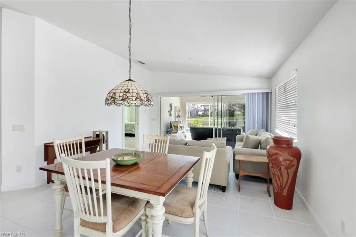 Dining room with lofted ceiling, light tile patterned flooring, and baseboards