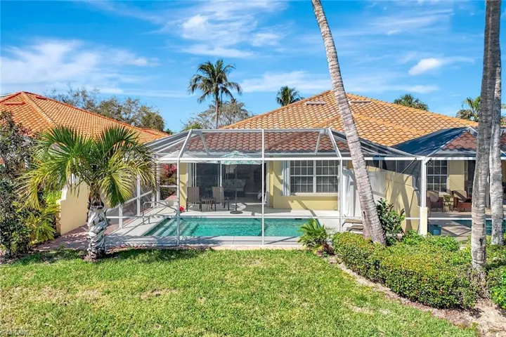 Rear view of house featuring a lawn, a tiled roof, a lanai, a patio area, and stucco siding