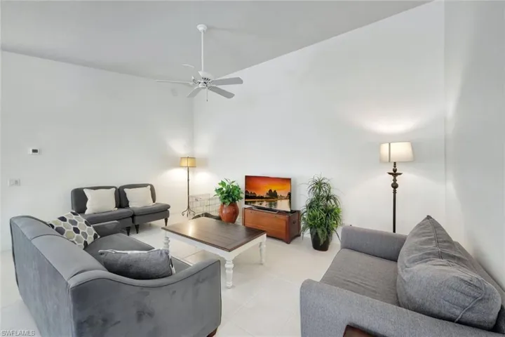 Living area with ceiling fan, a high ceiling, and light tile patterned flooring